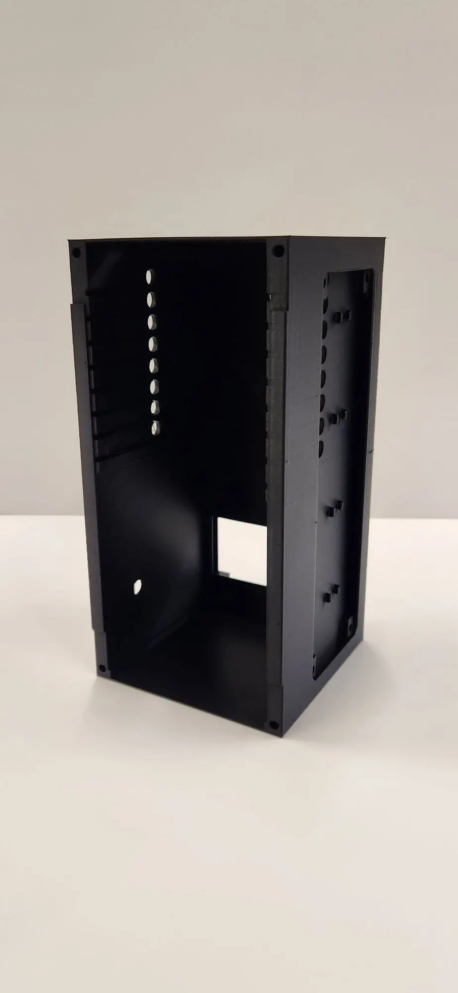 The black 3D-printed nanolab shell standing upright, open on one side, with a row of wire holes and a square cutout