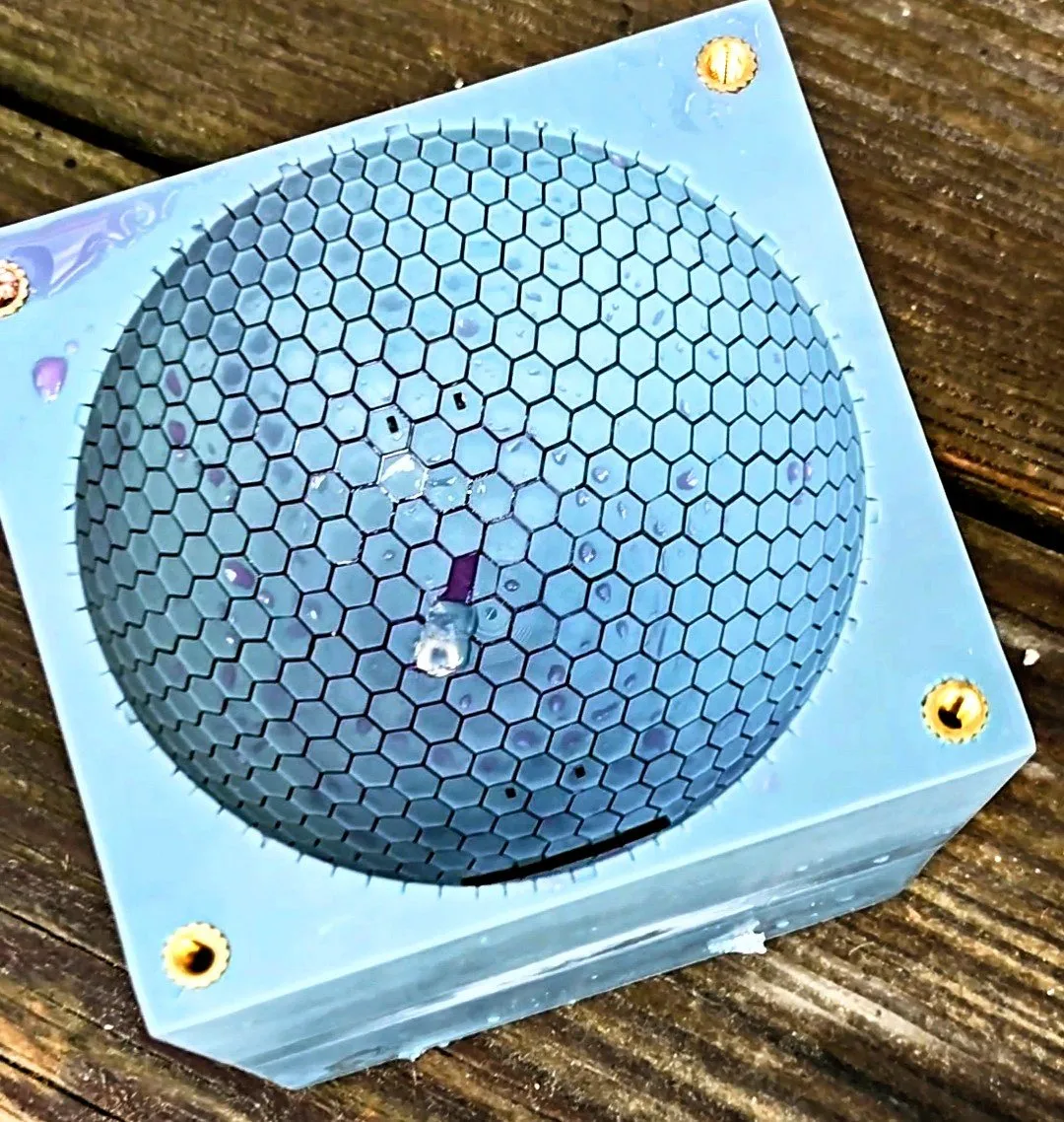 Printed light blue dome with hexagonal grooves, a spot of purple dyed water sitting in the channels