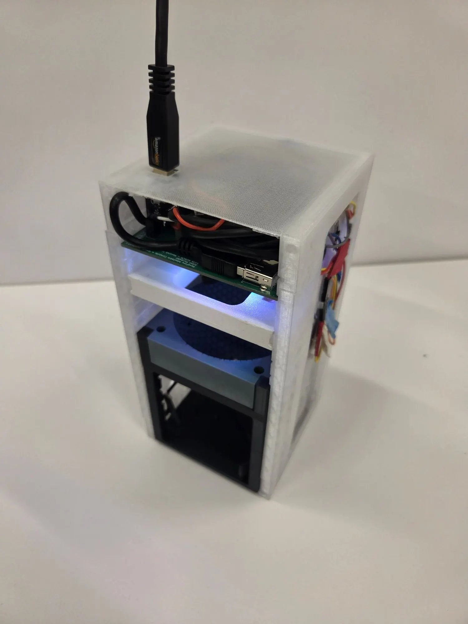 The assembled nanolab in a translucent white shell, lit from inside, with electronics visible on the shelves and a cable coming out the top