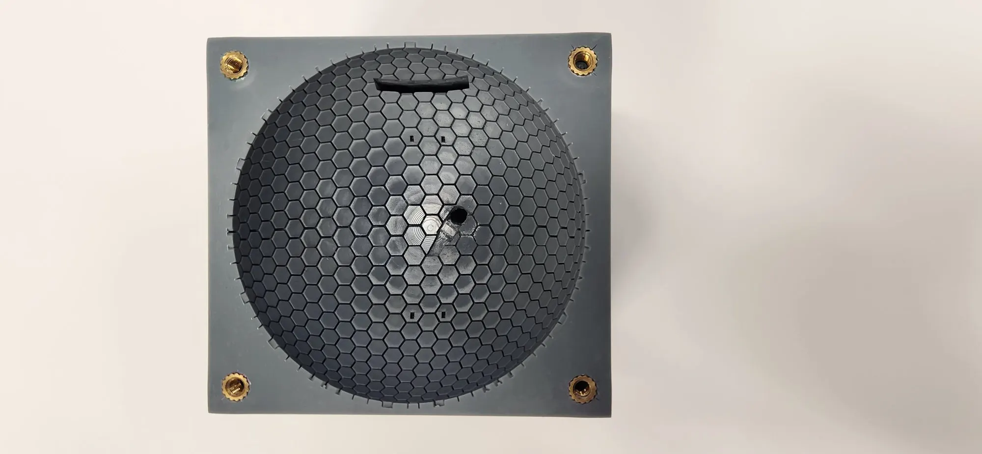 Top view of the HexaFlow capillary dome: a grey 3D-printed bowl covered in a lattice of tiny hexagonal channels, with brass inserts at the corners