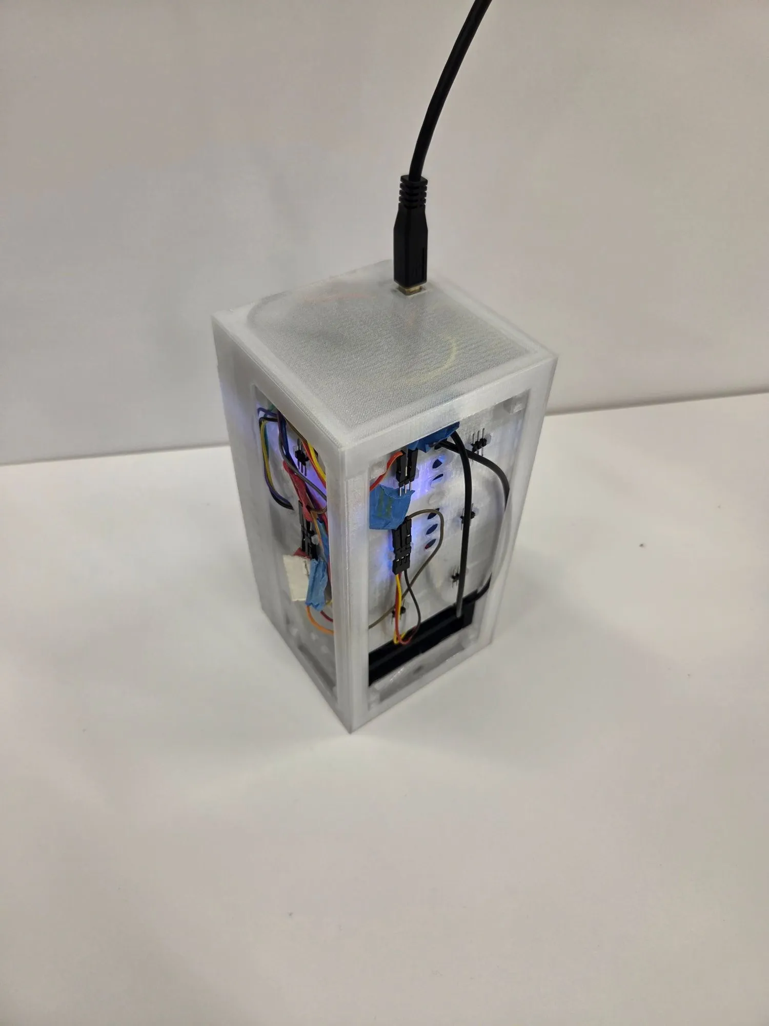 Assembled HexaFlow unit with frosted side panels, wiring and a circuit board visible inside, power cable on top